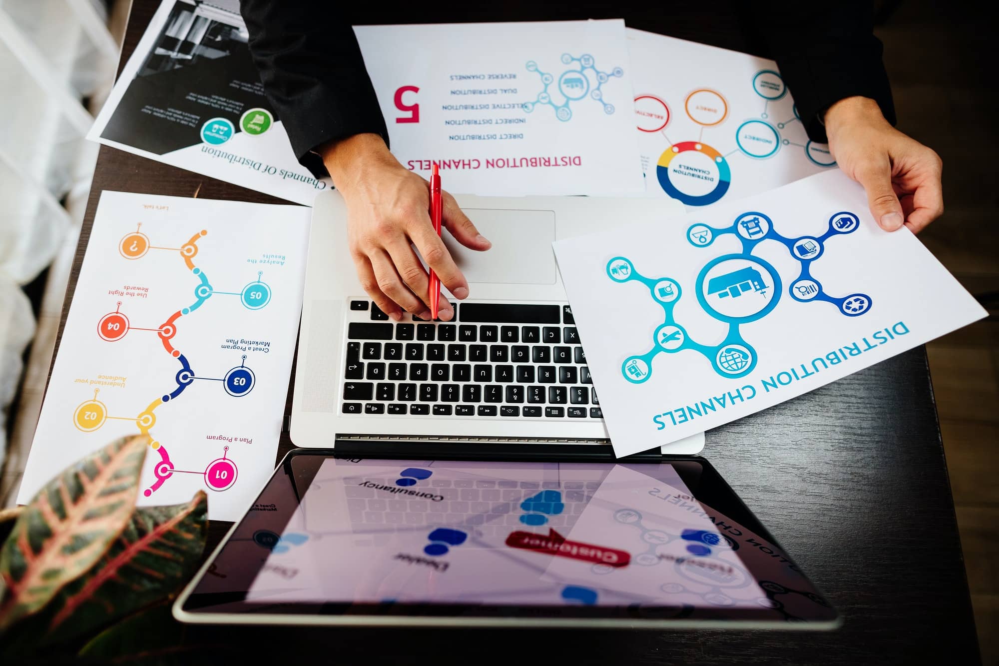 Person working on marketing materials for a client, in front of a laptop and scattered papers. Digital Marketing Agency and Web Design stoke-on-trent